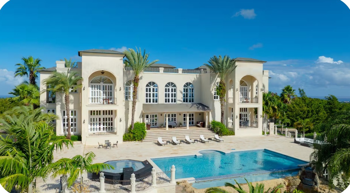 Mansion exterior and massive pool beneath palm trees